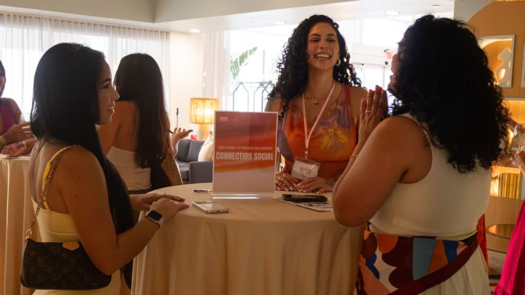 Three women laughing together at a She Cultivates Connection Social table with The Spark Collective