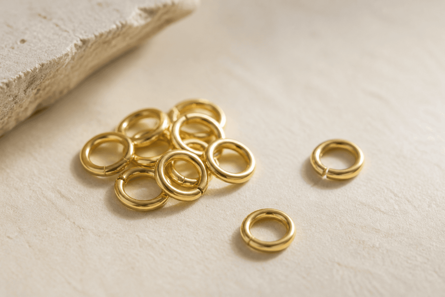 Polished gold jump rings on a light stone surface.